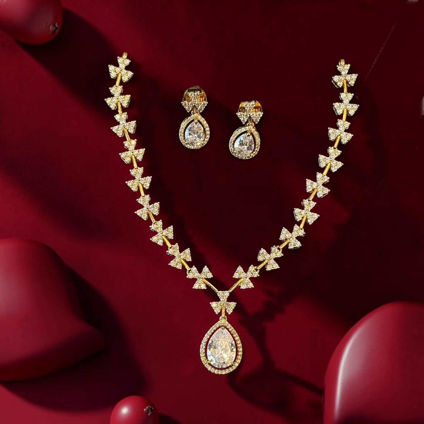 My Store gold teardrop pendant necklace and earring set with sparkling floral motifs on a deep red background
